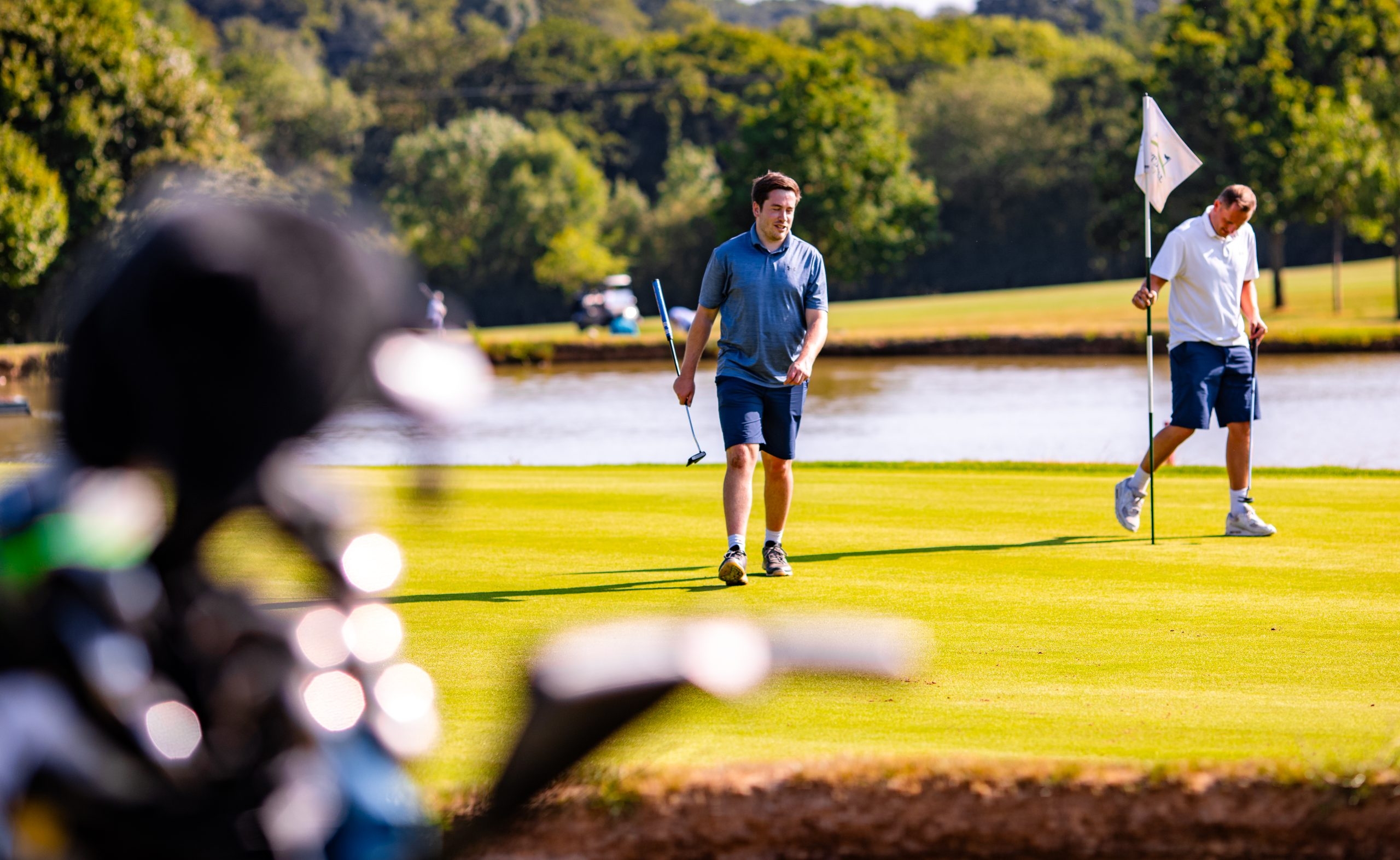 Golfers on green next to water feature on a sunny day on Toot Hill golf course