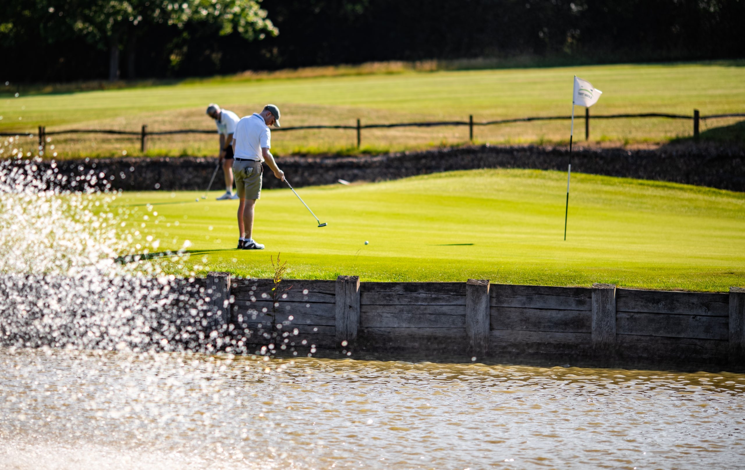 Golfers on green next to water feature on a sunny day on Toot Hill golf course